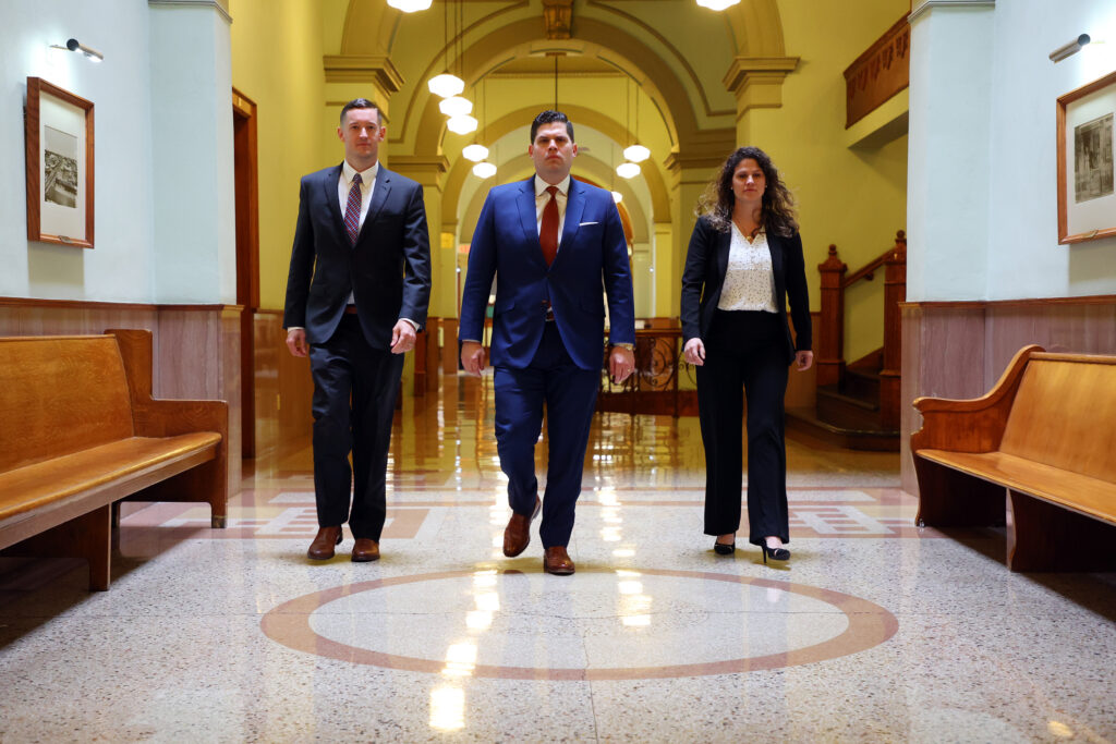 Norris Legal Group founder Graham Norris is flanked by two other attorneys as he walks down a courthouse hallway.