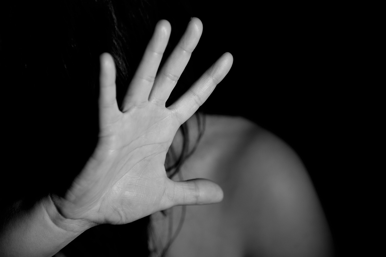 A black-and-white photo of a woman holding up her hand in self-defense.