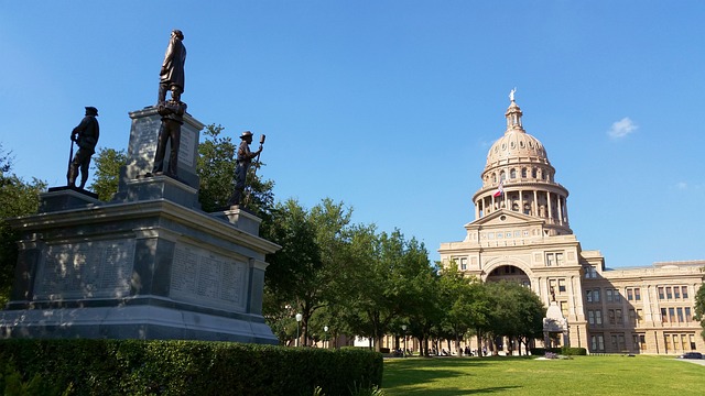 A photo of the Texas state capitol in Austin with statues in the foreground.