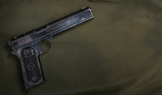 An overhead view of a black handgun on an olive green background.