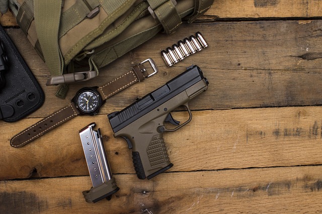 An overhead view of a pistol on a table next to a magazine, bullets, a watch, and a sack.