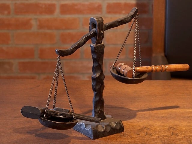 A scales of justice with a gun on one scale and a gavel on the other.