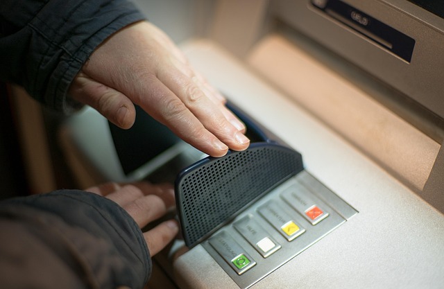 A close up of a pair of hands tampering with an ATM card reader.